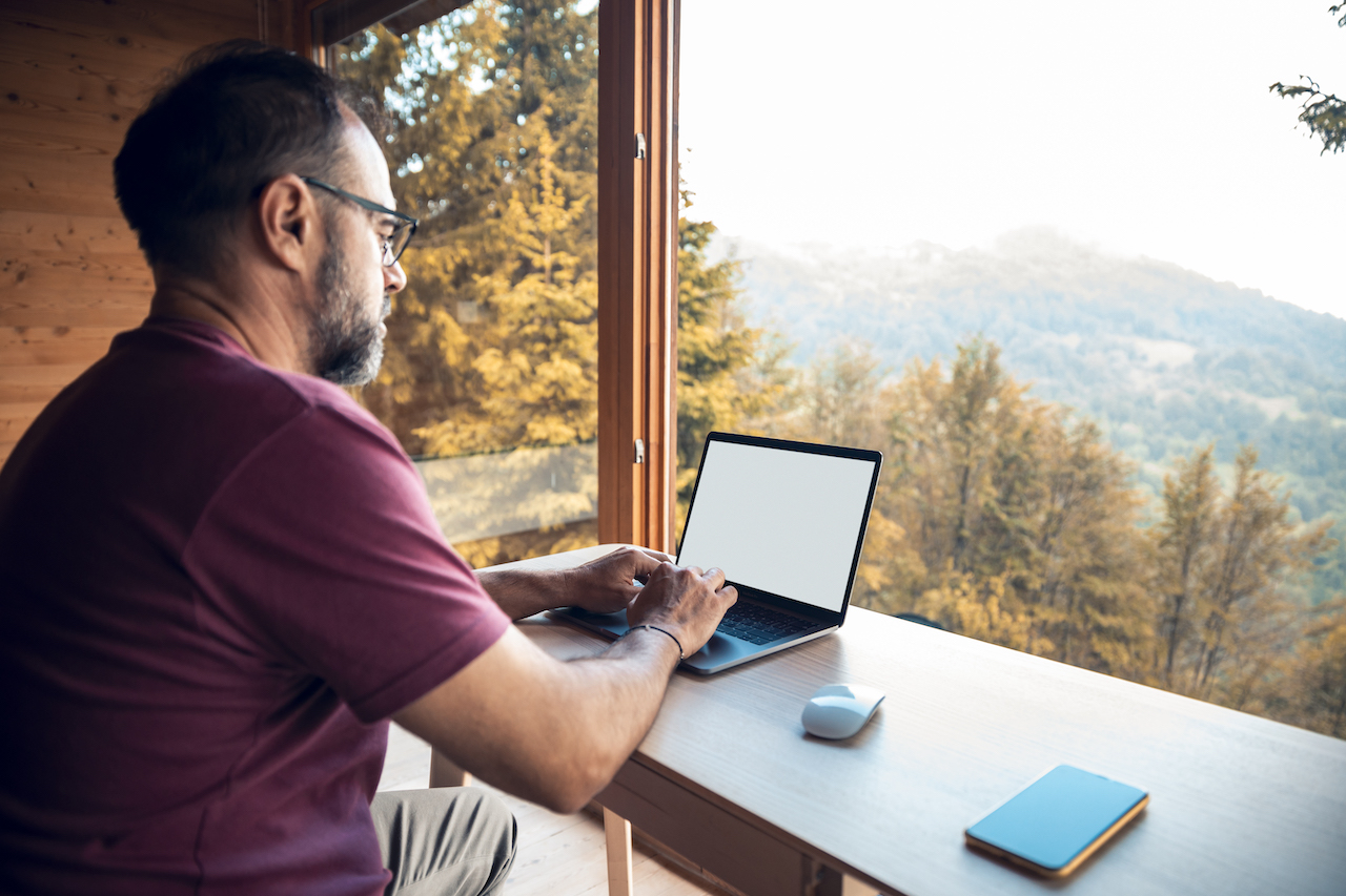 Person working on a laptop in a cabin in the woods.