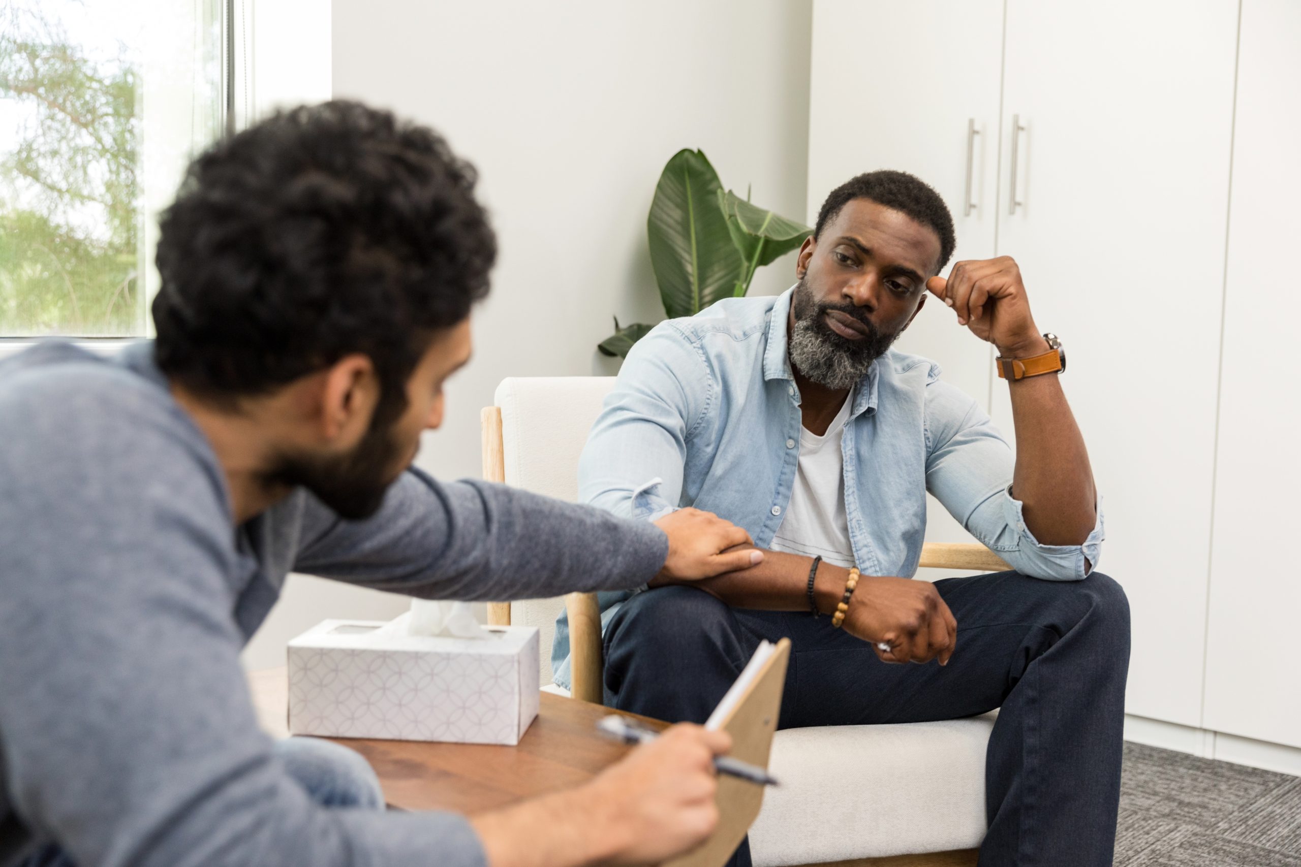 Male counselor reaches out to reassure distressed male patient